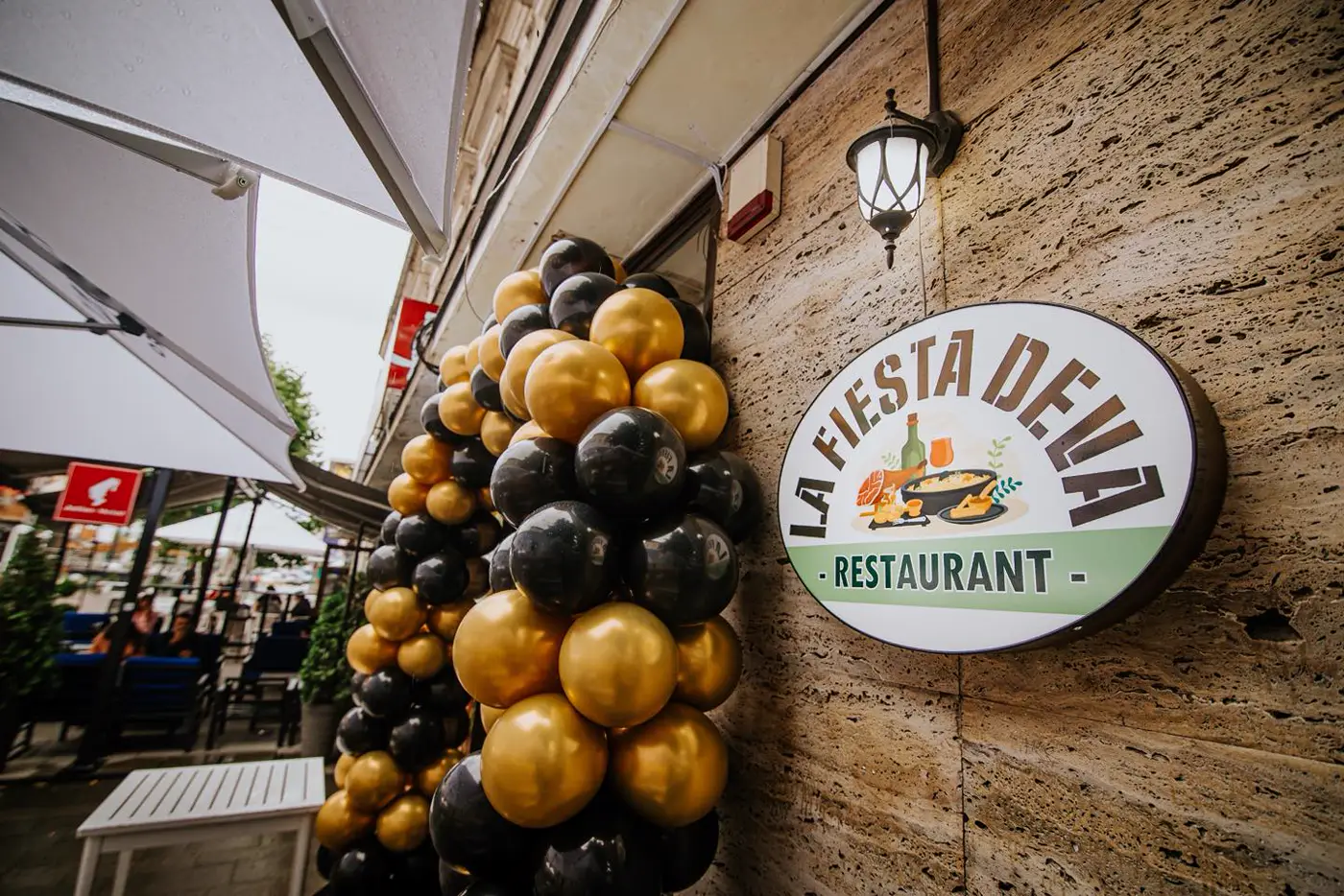 Intrarea restaurantului La Fiesta din Deva, cu firma ovală și terasa acoperită